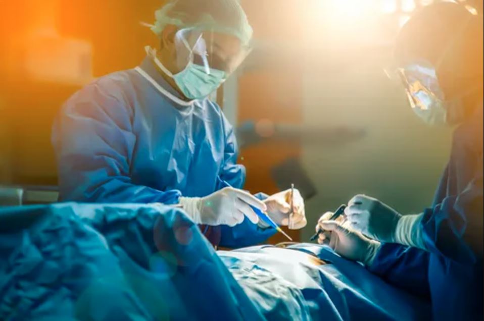 Two surgeons in scrubs and masks are focused on performing surgery in a sterile operating room.