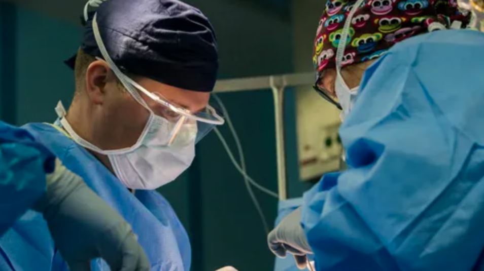 Surgeons in scrubs and masks diligently performing surgery in a sterile operating room environment.