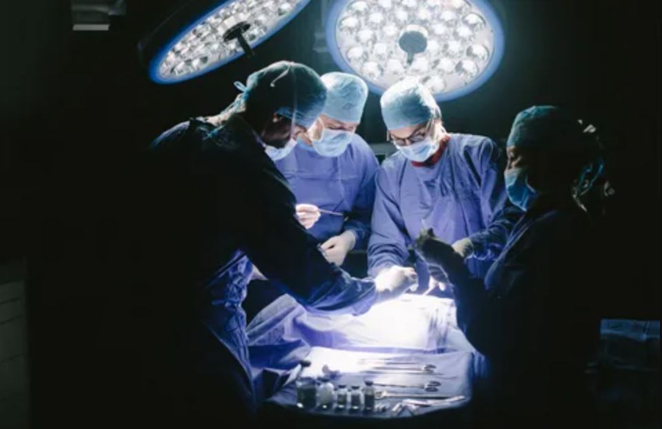 Surgeons skillfully conducting a surgical procedure in a dimly lit operating room, focused and precise in their actions.