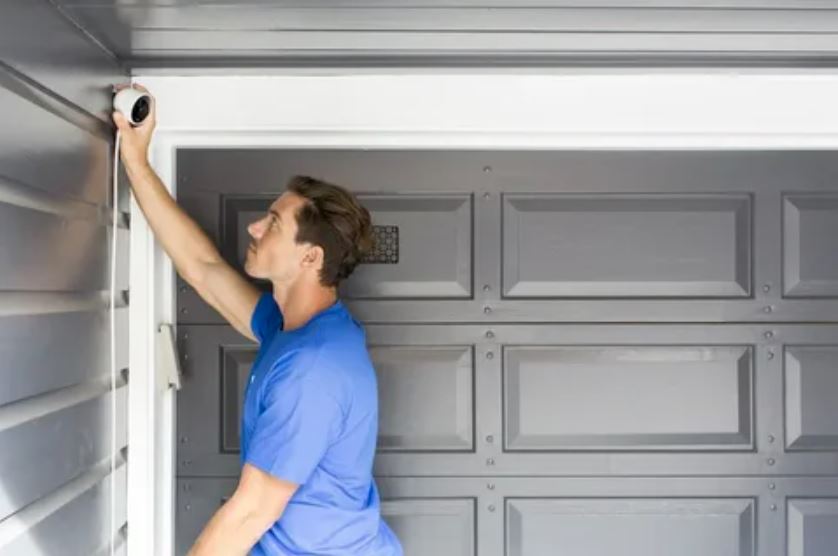 A man carefully installs a door in a garage, demonstrating skill and attention to detail in his work.