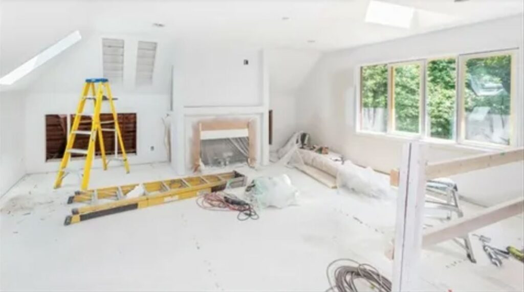 A bright room featuring white walls and a wooden ladder leaning against one side.