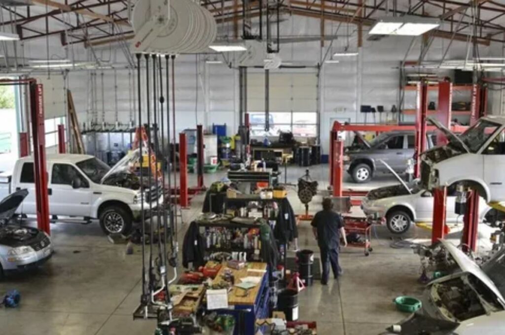 A busy car repair shop filled with various vehicles and technicians diligently working on repairs and maintenance tasks.